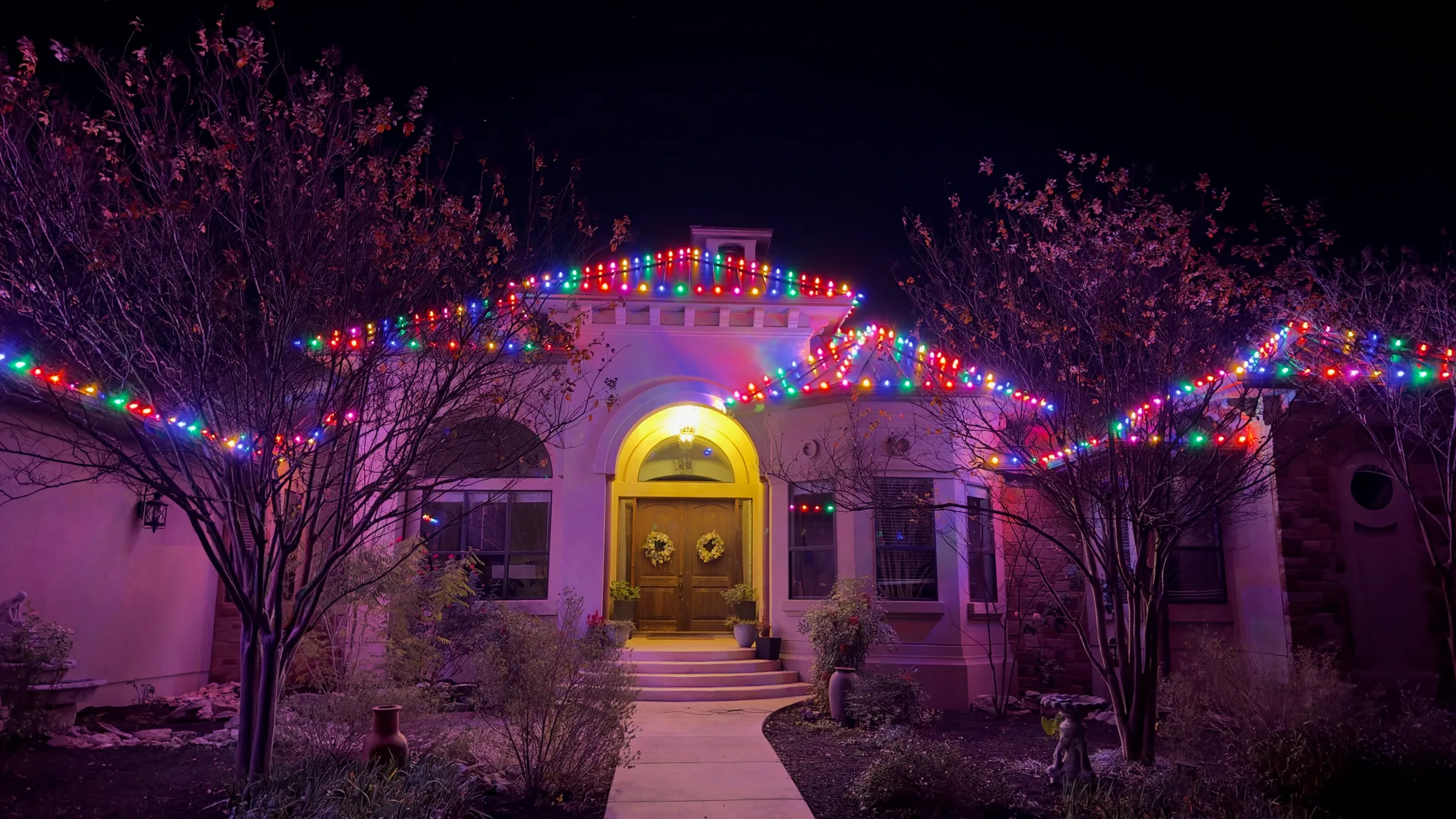 Upscale home lit at night, full roofline & landscape lighting
